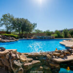 Summer home with a bright blue pool with natural landscaping