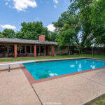 Summer home with a backyard pool with green surroundings